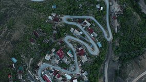 Incredible serpentine in the mountains. Aerial View of settlement in the mountains, built on a winding road. Mountain landscape, infrastructure in remote regions. 10 bit Video