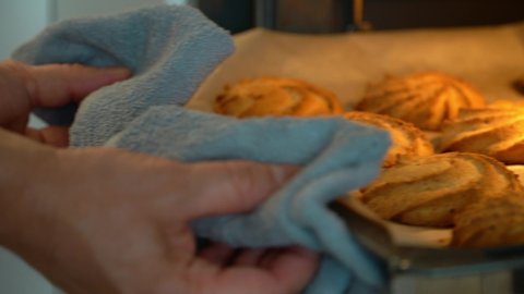 Close up of hands open oven door and take out hot baking sheet with fresh baked cookies in kitchen. Bakery products.