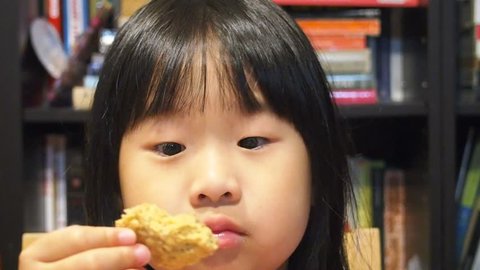 Beautiful asian toddler girl eating cookies