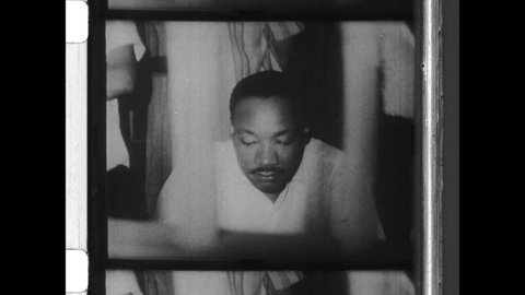 1950s Birmingham, AL. Civil Rights Leader Martin Luther King is arrested, finger printed, mug shot and placed in jail cell for non violent protest. 4K Overscan of Vintage Archival 16mm Newsreel Film