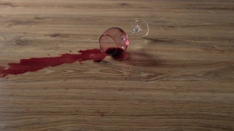 A glass of red wine falls onto the laminate in slow motion