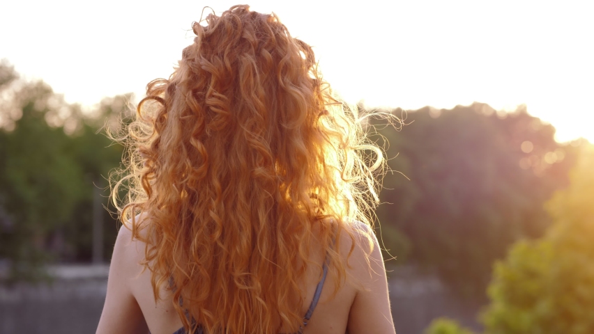 Back view of red-haired woman enjoying the panorama of the city