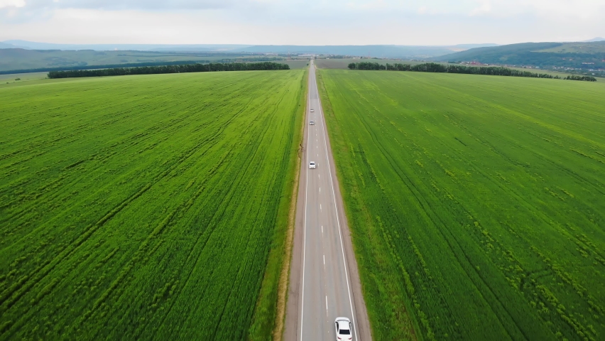 Aerial drone view. White car driving through road among agriculture fields and green countryside, drone following car. | Shutterstock HD Video #1084594387