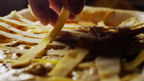 Preparation of lasagne, placing yolk dough strips top layer, italian food shot