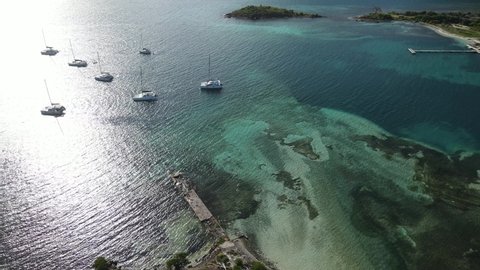 Descending aerial to large yachts in Jost Van Dyke shallow harbor near Foxy's Taboo