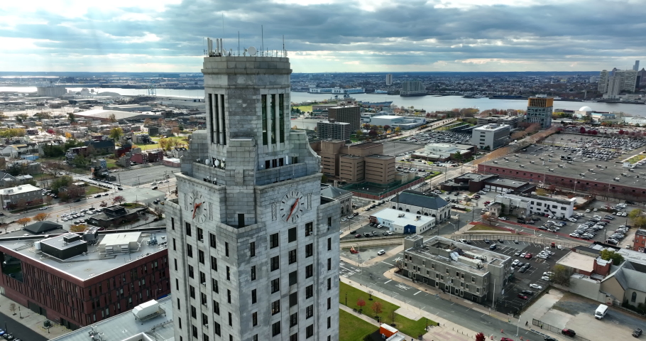 Camden City Hall in New Jersey. Aerial orbit of building with Philadelphia cityscape skyline and Ben Franklin bridge over Delaware River. Establishing shot.