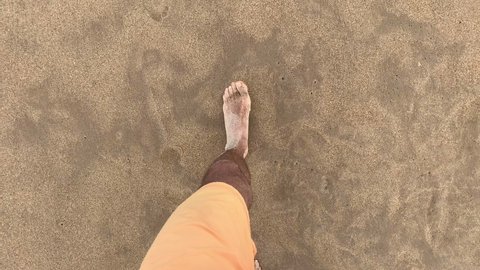 Person POV feet walking at beach shore entering sea water