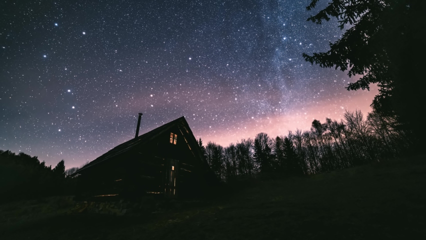 Time lapse Fairytale night sky with millions stars of milky way galaxy above wooden hut in wild forest nature Astronomy