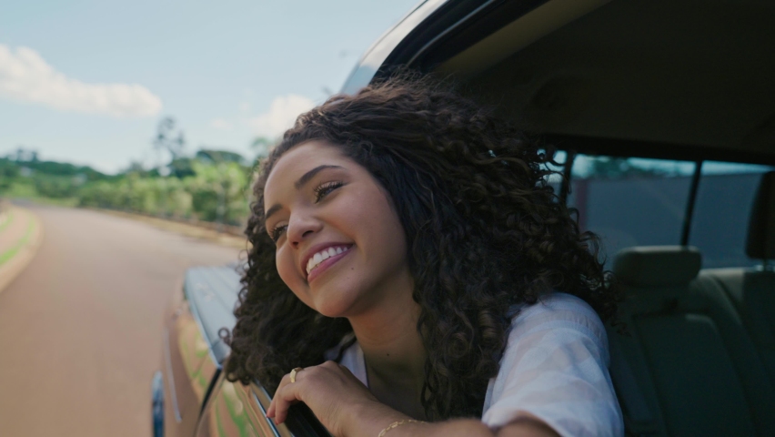 Latin woman in car window. Car trip. Curly hair in wind. Girl looks out of car window. Brazilian travel concept by car. Cinematic 4K | Shutterstock HD Video #1084603402