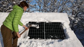 A girl clears the solar panel of snow and ice. Work on the roof of the house. Cleaning with a shovel. Bright sunny day. - Powered by Shutterstock - Get 15% off with code: PIKWIZARD15