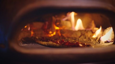 A delicious homemade turkish pita is being cooked in a wood oven close-up. Wood burning in the oven. Traditional, Authentic home bakery. Homemade pita bread and oven with flame inside. Turkish food.