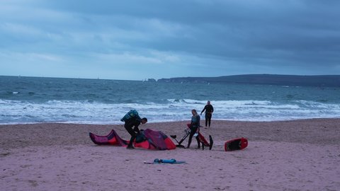 Bournemouth, UK. November 10, 2021. Kite surfers preparing a kite on the beach in a windy environment with Harrys rock cliffs on the background.