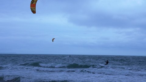 Kite surfer practising acrobatics in a Northern open ocean bay with emerald sea on a windy day near Old Harries rock cliffs.