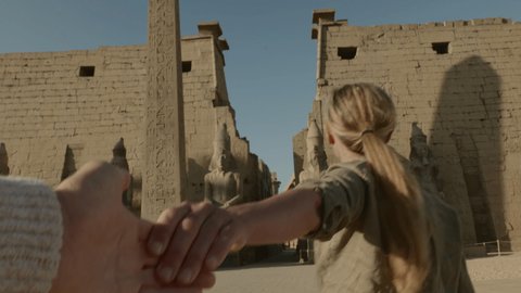 Follow me to Egypt. Female tourist leading way to magnificent temple in Luxor. People travel concept - Girl holding man at temple traveling together