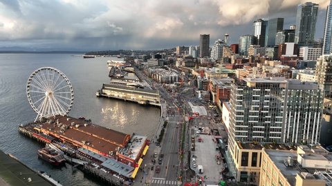 Birdseye drone dolly shot of the Seattle Great Wheel with downtown waterfront, Alaskan Way and the Seattle Aquarium