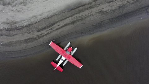 Man Preparing Alaskan Floatplane On The Shore For Flight. aerial top-down
