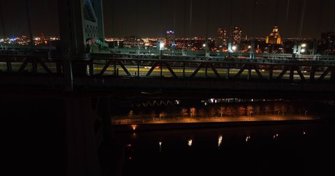 Side profile shot of suspension bridge at night. Car traffic cross urban city highway. American Ben Franklin Bridge. Aerial shot.
