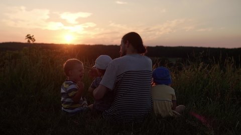 people in park. happy family walk at field. dad with many children on top of mountain in tall grass before sunset. parents and fun kids look into the distance. summer, fatherhood, childhood concept