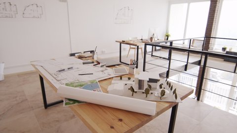 No people shot of long wooden desk with house plans, drawings and layout at creative architects office