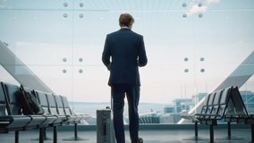 Airport Terminal: Businessman with Rolling Suitcase Walks, Uses Smartphone App for e-Business. Back View of Traveling Man Waiting for a Flight in Boarding Lounge of Airline Hub with Airplanes Arriving - Powered by Shutterstock - Get 15% off with code: PIKWIZARD15
