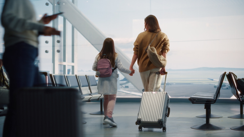 Airport Terminal: Beautiful Mother and Cute Little Daughter Wait for their Vacation Flight, Looking out of Window for Arriving and Departing Airplanes. Young Family in Boarding Lounge of Airline Hub Royalty-Free Stock Footage #1084637086