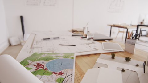 No people shot of house layout, plans and drawings laying on long wooden desk at architects office
