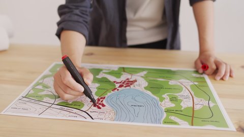Midsection of unrecognizable architect coloring map of area with felt pen on desk in office