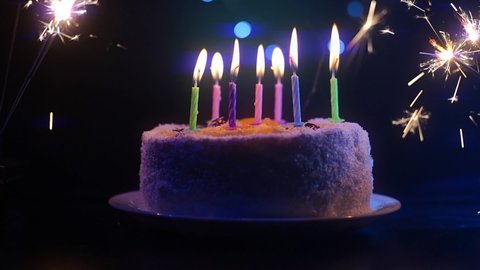A birthday cake with candles and sparklers on both sides without guests