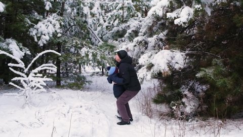 A father tosses his son up, spending time in the winter snowy forest