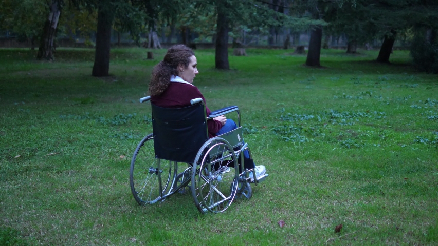 living with disabilities - young woman using wheelchair alone at the park 