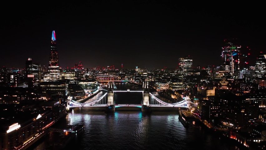Establishing Aerial View Shot of London City Skyline at night with the Tower Bridge in foreground, sky garden by the Thames River, United Kingdom, UK