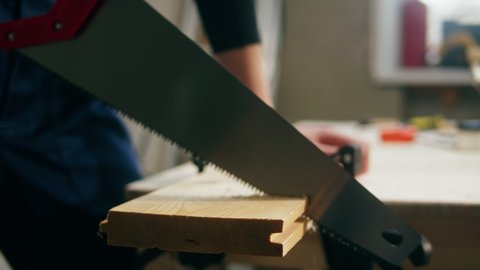 Woman builder sawing wooden board close-up. Female carpenter cutting wood, using saw, making diy furniture. Renovation concept. Building new house or flat.