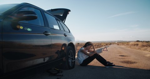 Frustrated attractive young woman has tire flat car accident during travel on country road and unfortunately trying to fix it by herself without knowledge 