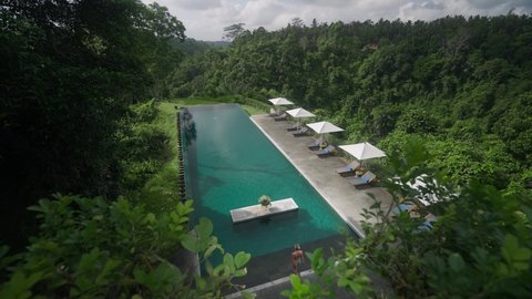 Woman walking into luxury infinity pool in tropical Bali jungle resort
