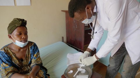 African doctor opening up a swab test kit in a rural African hospital.