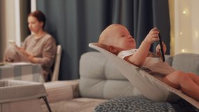 Mother with baby use smart phones in different corners of the room, mom using social media, cute little child watching movie on phone screen. People and modern mobile technology concept.