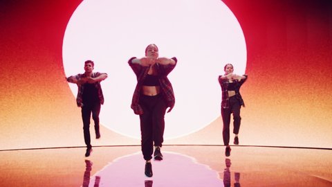 Diverse Group of Three Professional Dancers Performing a Hip Hop Dance Routine in Front of a Big Led Wall Screen with VFX Animation During a Virtual Production in Studio Environment. 105 BPM Song.