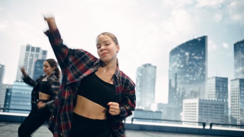 Diverse Group of Three Young Professional Dancers Performing a Hip Hop Dance Routine in Close Up in Front of a Big Led Screen with Modern Urban Skyline with Skyscrapers in Studio Environment.