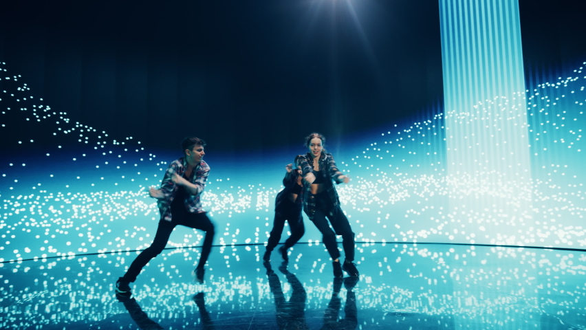 Diverse Group of Three Professional Dancers Performing a Hip Hop Dance Routine in Front of a Big Led Wall Screen with VFX Animation During a Virtual Production in Studio Environment. 105 BPM Song. | Shutterstock HD Video #1084666597