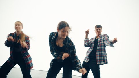 Diverse Group of Three Young Professional Dancers Performing a Hip Hop Dance Routine in Close Up in Front of a Big Led Screen with Bright White Background in Studio Environment.