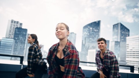 Diverse Group of Three Young Professional Dancers Performing a Hip Hop Dance Routine in Close Up in Front of a Big Led Screen with Modern Urban Skyline with Office Skyscrapers in Studio Environment.