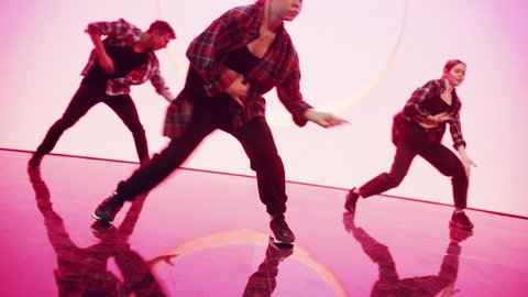 Close Up on Legs of Three Professional Dancers Performing a Hip Hop Dance Routine in Front of a Big Led Screen with VFX Animation During a Virtual Production in Studio. 105 BPM Song.