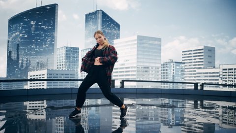 Stylish Young Professional Female Dancer Performing a Hip Hop Dance Routine in Front of Big Led Wall Screen with Modern City Skyline with Office Skyscrapers in Studio Environment.