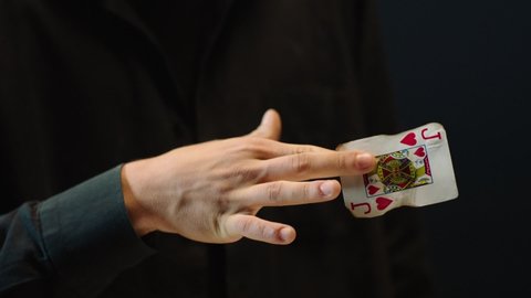 Close-up of a Magician Hand Performing Card Trick . Burning card on black Background with smoke . Card Mechanic rotating flaming card in hand . Shot on ARRI Alexa cinema camera in Slow Motion 