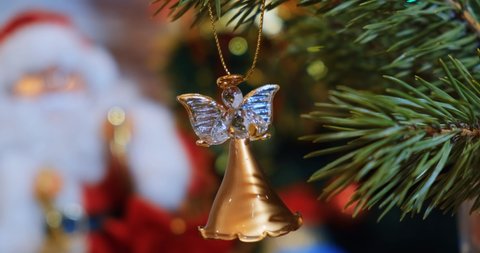 A Christmas tree toy in the form of an angel hangs on a branch of a Christmas tree. The concept of New Years holidays, Christmas. Festive background