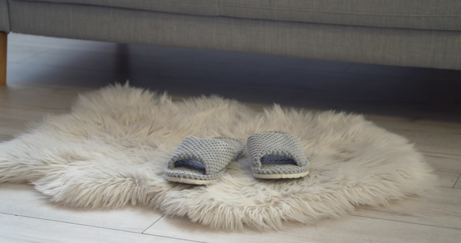 Young woman putting on slippers at home