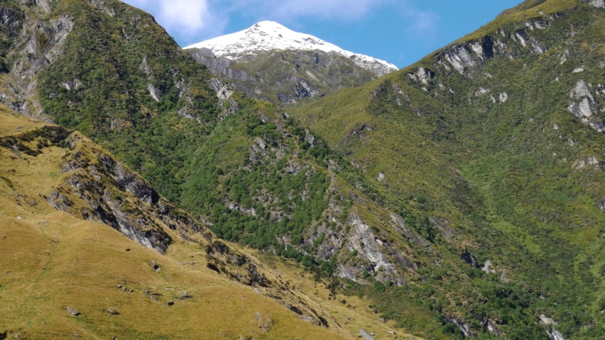 Panorama shot of vast mountain range with snowy peak in Fiordland National Park during summer