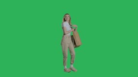 Young woman in casual clothes walks with shopping bag on a Green Screen, Chroma Key. 4k UHD perspective view isolated video.