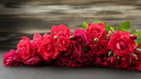  Female hands putting Greeting Card For Mother's Day on red bright roses bouquet buds
with rustic background, 4K  video shot.