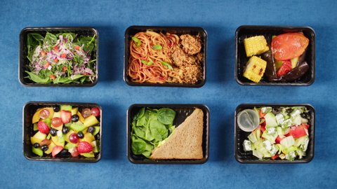 Closing take away meals top view, Food delivery in disposable containers, balanced nutrition. Fresh cooked portions in lunch boxes, vegetarian dishes. Healthy eating, diet. Catering service concept.  Video de stock
